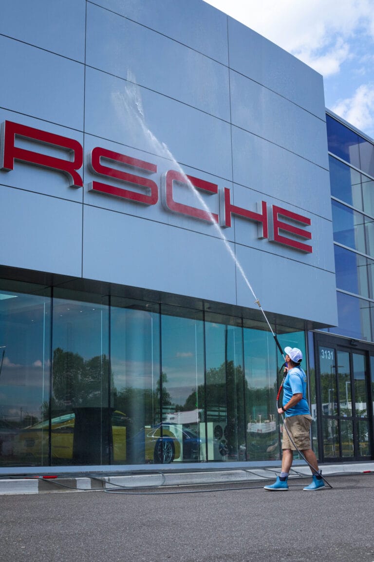Commercial building exterior being power washed, removing dirt and grime.